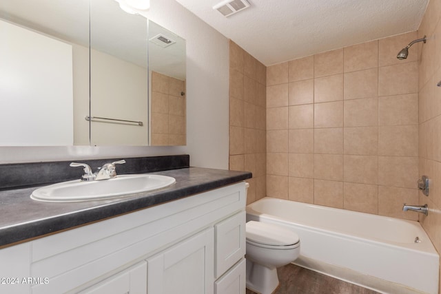 full bathroom with vanity, a textured ceiling, wood-type flooring, toilet, and tiled shower / bath