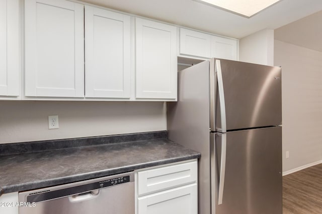 kitchen with appliances with stainless steel finishes, white cabinetry, and hardwood / wood-style floors