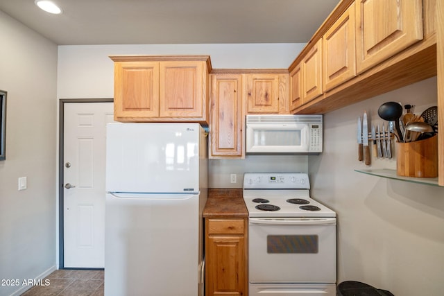 kitchen featuring tile patterned flooring, white appliances, and baseboards