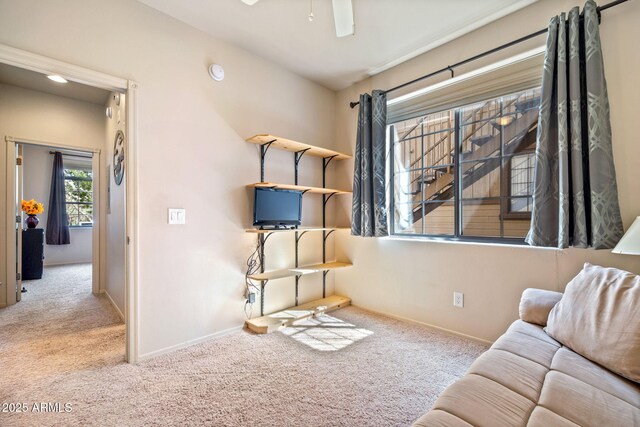 living area with baseboards, carpet, and a ceiling fan