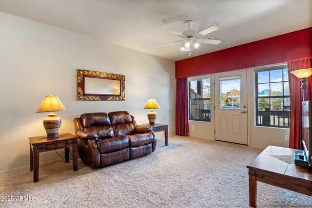 carpeted living area with baseboards and a ceiling fan