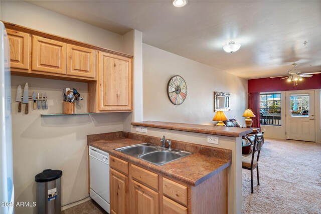 kitchen featuring a peninsula, light brown cabinetry, a sink, light carpet, and dishwasher