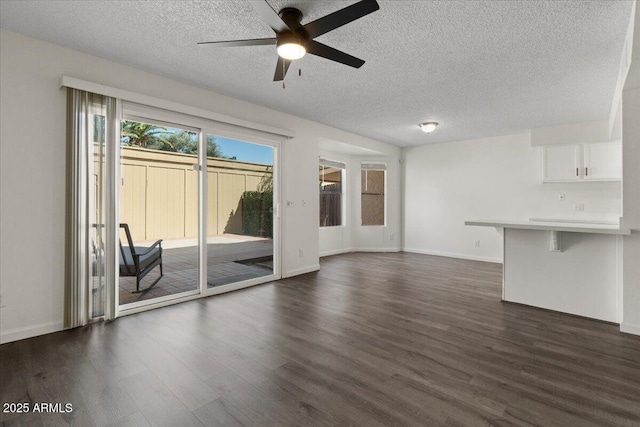 unfurnished living room with dark wood finished floors, a ceiling fan, baseboards, and a textured ceiling