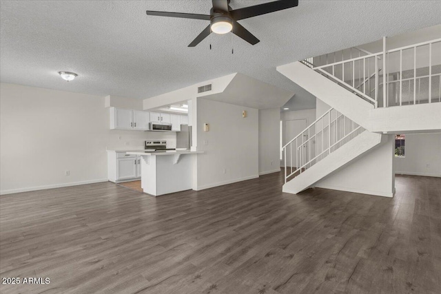 unfurnished living room featuring dark wood-type flooring, stairway, visible vents, and a textured ceiling