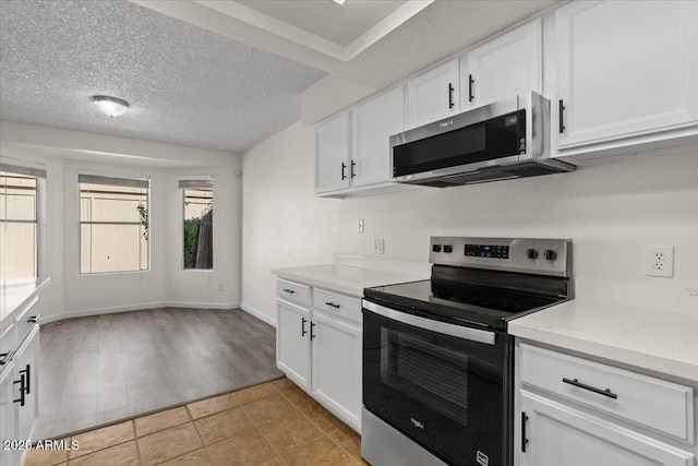 kitchen with white cabinets, appliances with stainless steel finishes, and light tile patterned flooring