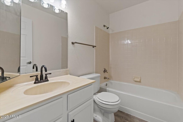 full bath featuring toilet, wood finished floors, vanity, and shower / washtub combination
