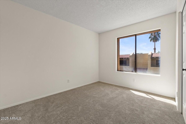 spare room featuring a textured ceiling, baseboards, and carpet floors