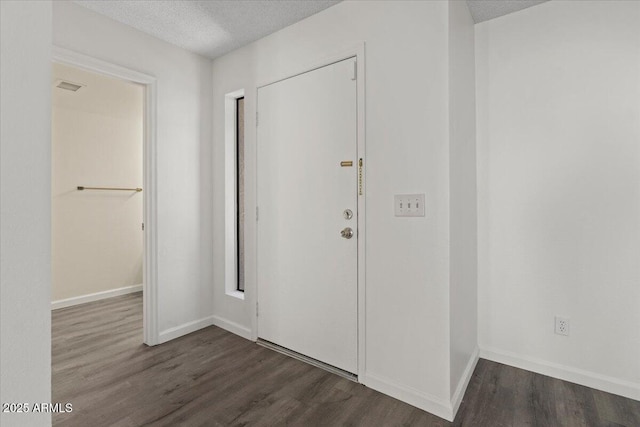 entryway featuring a textured ceiling, baseboards, dark wood-style floors, and visible vents