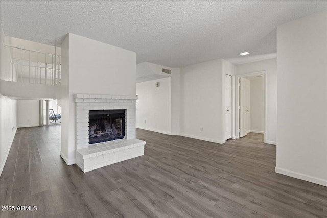 unfurnished living room with visible vents, baseboards, a textured ceiling, a fireplace, and dark wood-type flooring