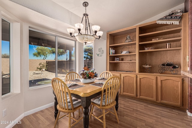 dining space with dark wood-type flooring and an inviting chandelier