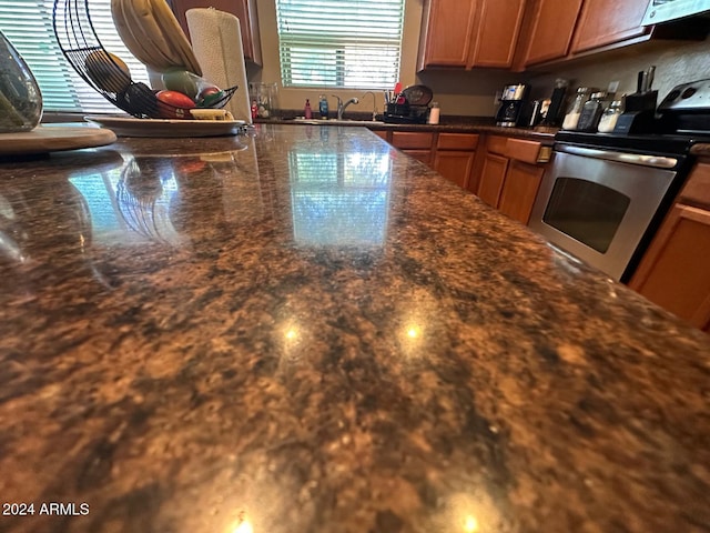 kitchen featuring dark stone countertops, stainless steel electric range oven, and sink