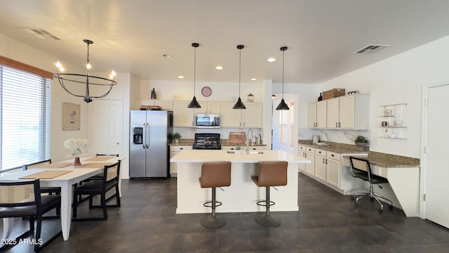 kitchen with appliances with stainless steel finishes, pendant lighting, sink, white cabinets, and a center island with sink