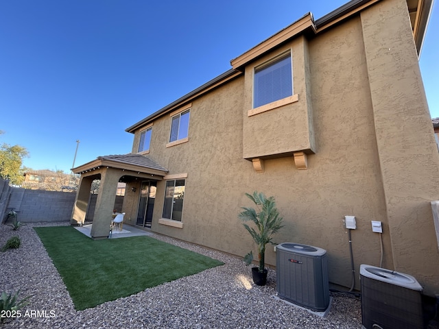 rear view of property featuring a yard, central AC, and a patio area