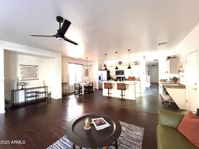 living room featuring dark hardwood / wood-style flooring, ceiling fan, and a textured ceiling