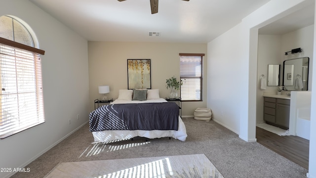 carpeted bedroom with multiple windows, ceiling fan, and ensuite bathroom