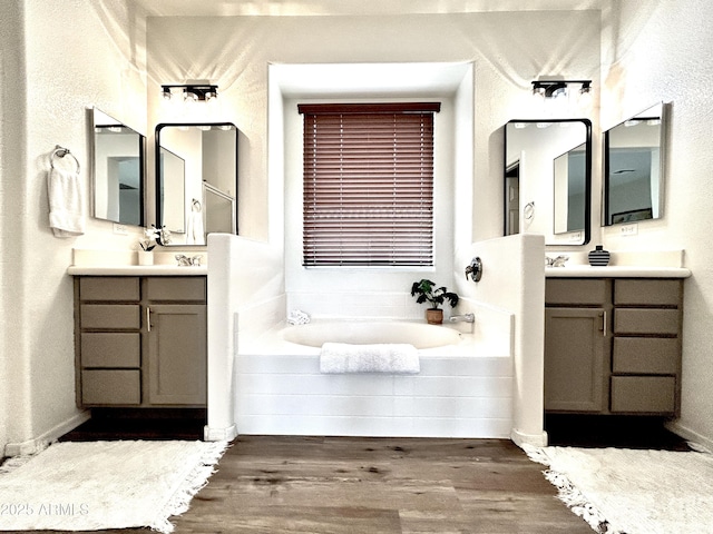 bathroom featuring vanity, tiled tub, and hardwood / wood-style floors