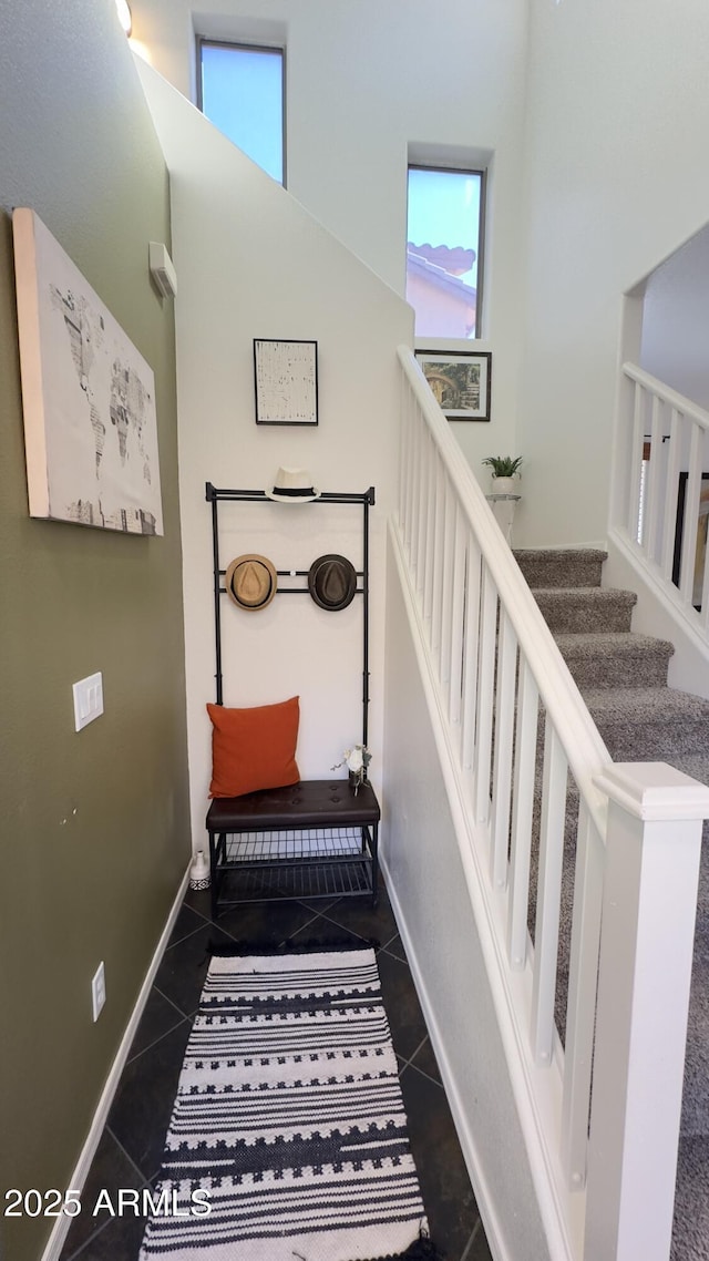 stairway with a towering ceiling and tile patterned floors