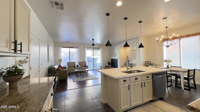 kitchen with sink, ceiling fan with notable chandelier, an island with sink, decorative light fixtures, and stainless steel dishwasher