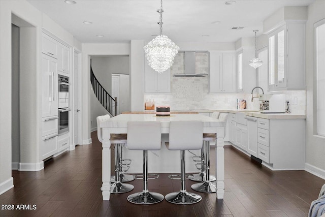 kitchen with a kitchen bar, a center island, wall chimney exhaust hood, and tasteful backsplash