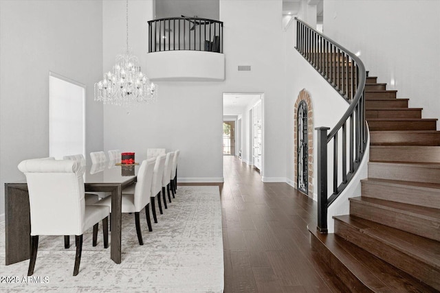 dining space featuring wood finished floors, visible vents, baseboards, stairway, and an inviting chandelier