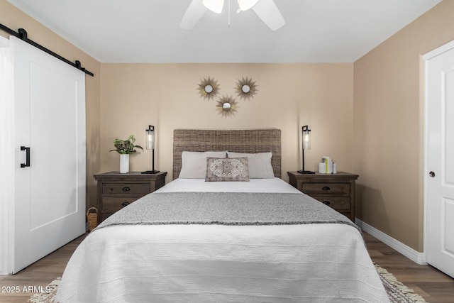 bedroom with ceiling fan, hardwood / wood-style floors, and a barn door