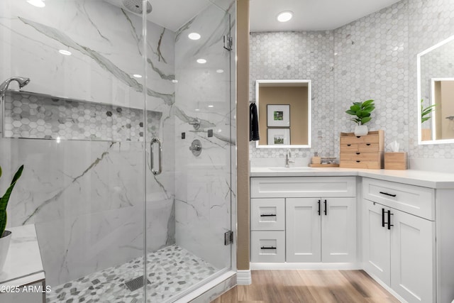 bathroom with hardwood / wood-style floors, a shower with shower door, and vanity