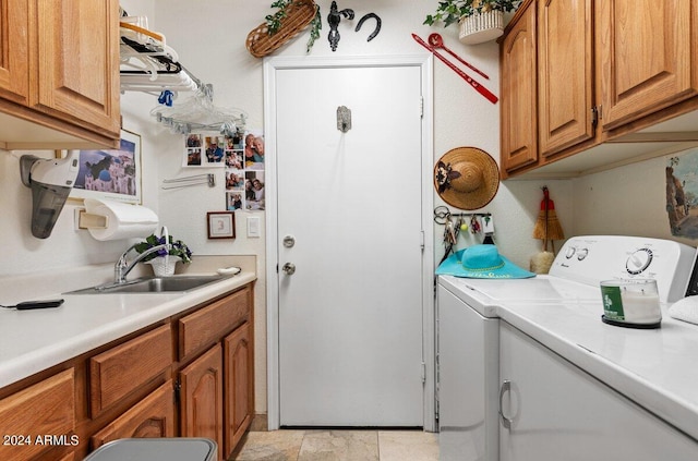 clothes washing area featuring separate washer and dryer, cabinets, and sink