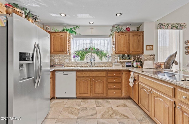 kitchen featuring electric cooktop, stainless steel fridge with ice dispenser, sink, decorative backsplash, and white dishwasher