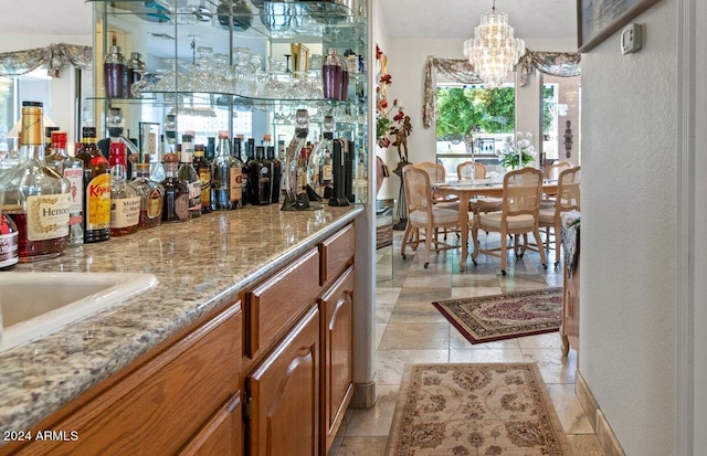 bar featuring an inviting chandelier, light stone counters, and pendant lighting