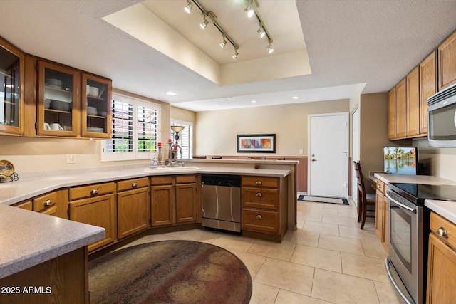 18780 N 94th Ave, Peoria, AZ 85382 - kitchen featuring appliances with stainless steel finishes, a peninsula, brown cabinets, light countertops, and light tile patterned floors