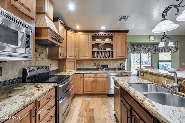 kitchen featuring light hardwood / wood-style flooring, decorative light fixtures, sink, light stone counters, and appliances with stainless steel finishes