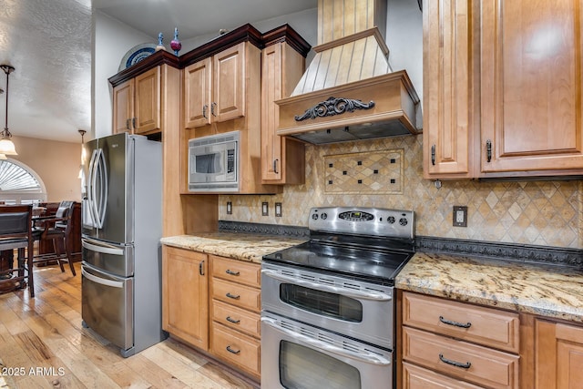 kitchen with hanging light fixtures, stainless steel appliances, backsplash, light stone counters, and custom exhaust hood