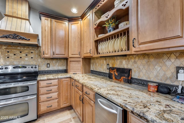 kitchen featuring range with two ovens, light stone countertops, custom range hood, light hardwood / wood-style floors, and backsplash