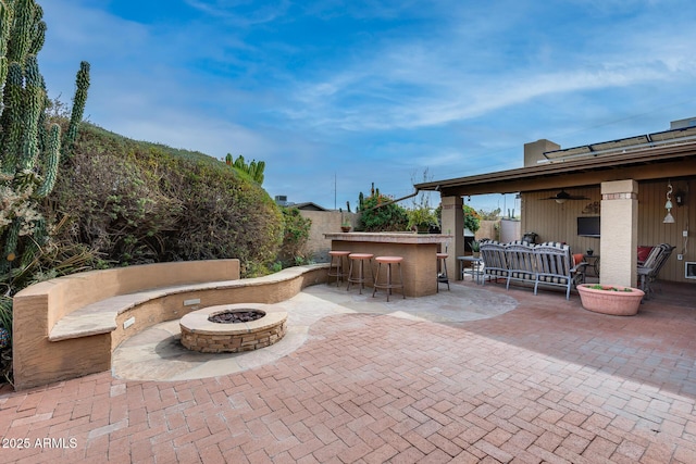 view of patio / terrace with ceiling fan, an outdoor living space with a fire pit, and exterior bar