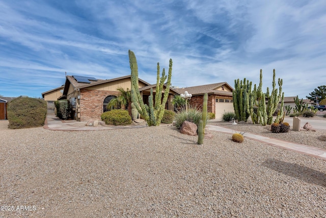 ranch-style home with a garage and solar panels