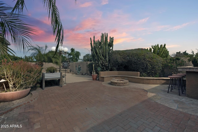 patio terrace at dusk featuring an outdoor fire pit and exterior bar