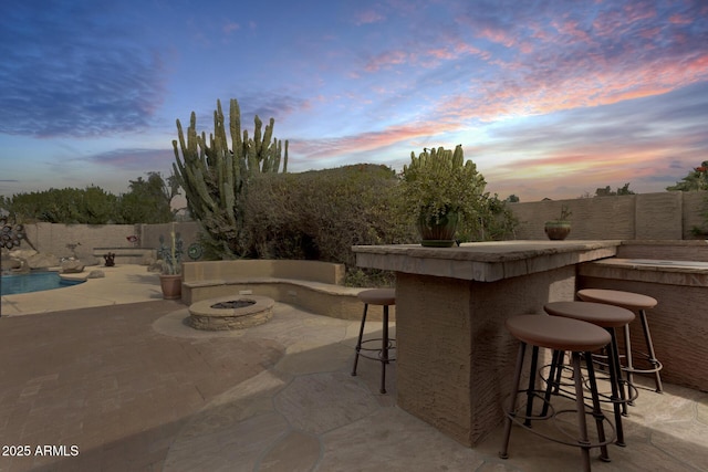 patio terrace at dusk with a fire pit and a bar