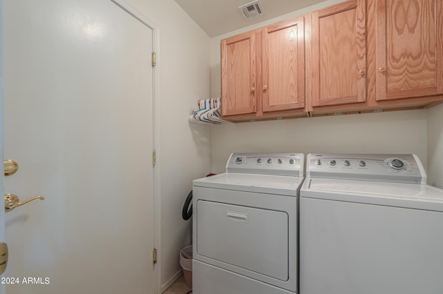 clothes washing area featuring cabinets and washer and dryer