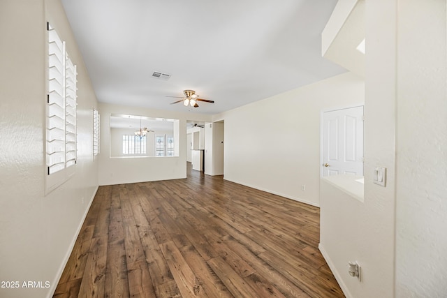 empty room with visible vents, ceiling fan with notable chandelier, baseboards, and wood finished floors