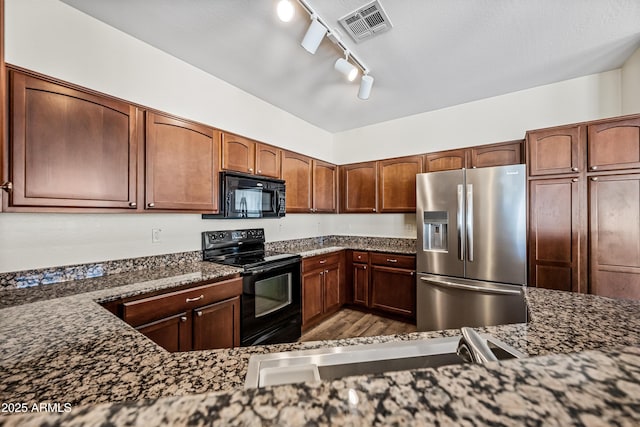 kitchen featuring black appliances, sink, dark stone counters, and track lighting