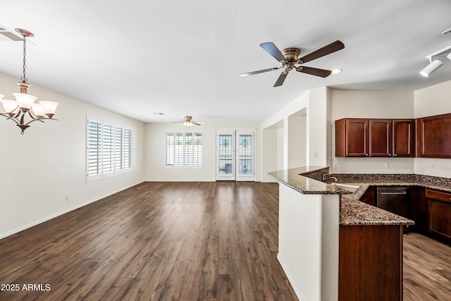 kitchen featuring sink, dark hardwood / wood-style flooring, dark stone countertops, decorative light fixtures, and ceiling fan with notable chandelier