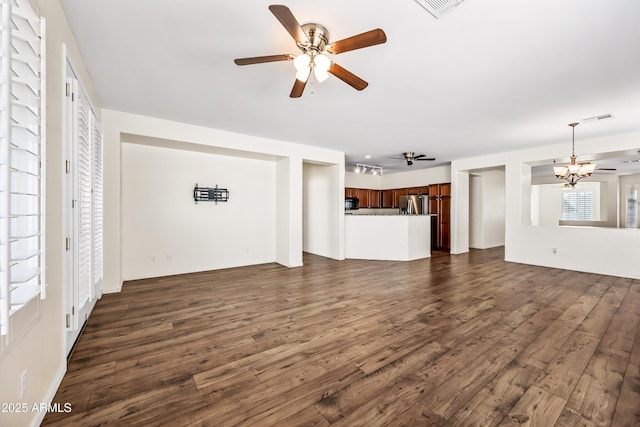 unfurnished living room with visible vents, ceiling fan with notable chandelier, and dark wood-style flooring