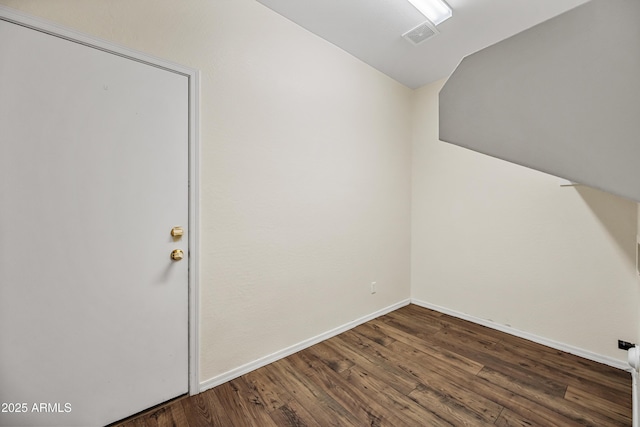 spare room featuring vaulted ceiling, wood finished floors, and baseboards