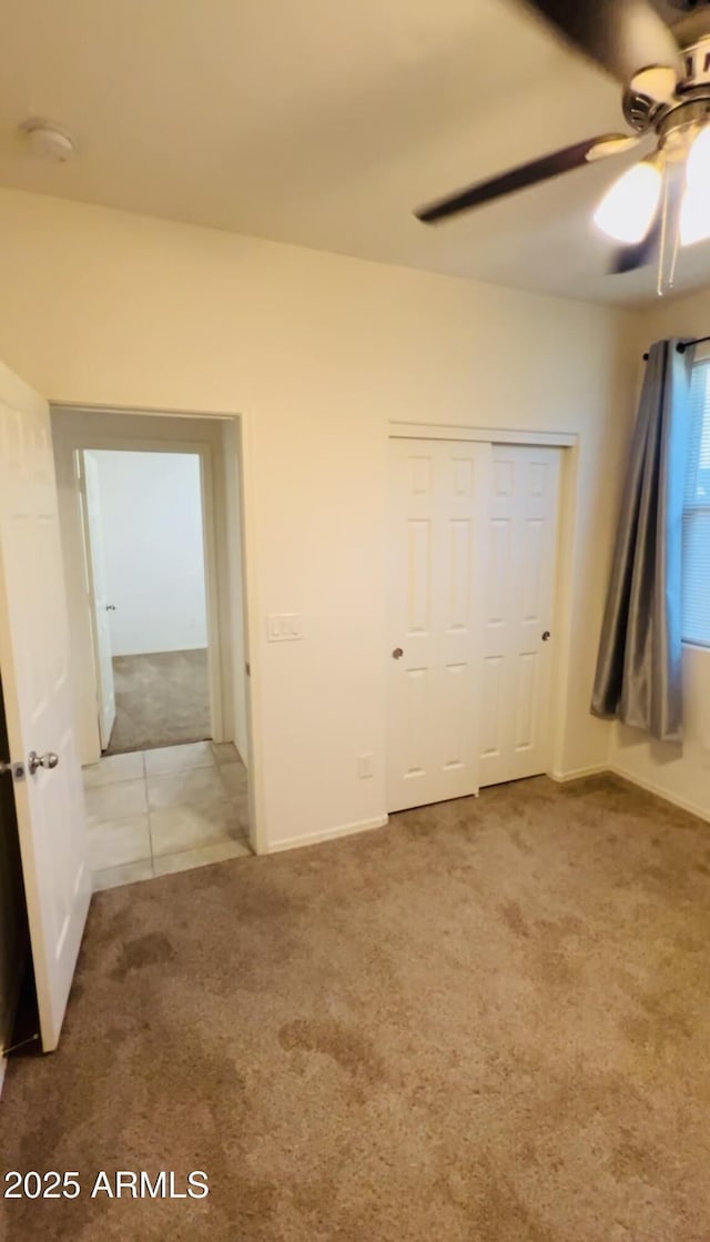 unfurnished bedroom with a ceiling fan, carpet, and a closet