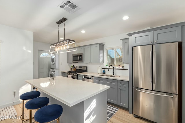 kitchen featuring pendant lighting, a kitchen island, stacked washer and dryer, and stainless steel appliances