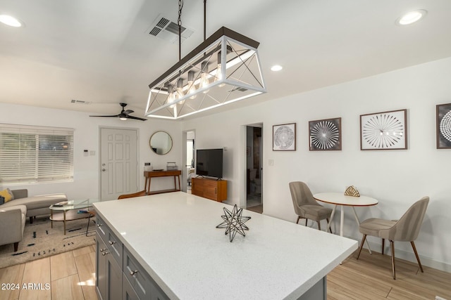 kitchen featuring gray cabinetry, ceiling fan, a center island, hanging light fixtures, and light hardwood / wood-style flooring