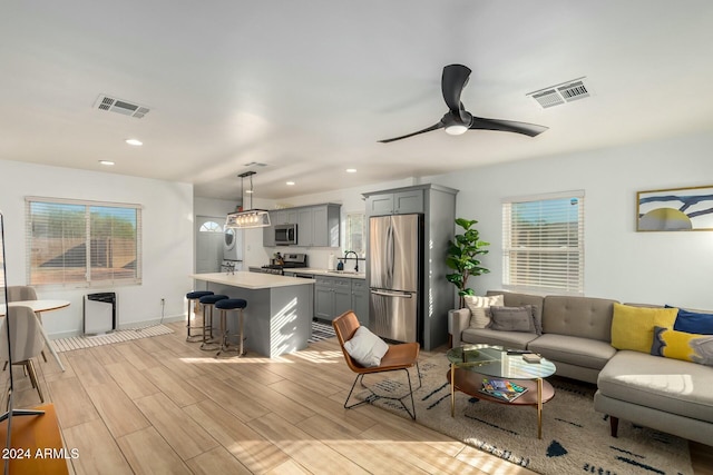 living room featuring ceiling fan, light wood-type flooring, and sink