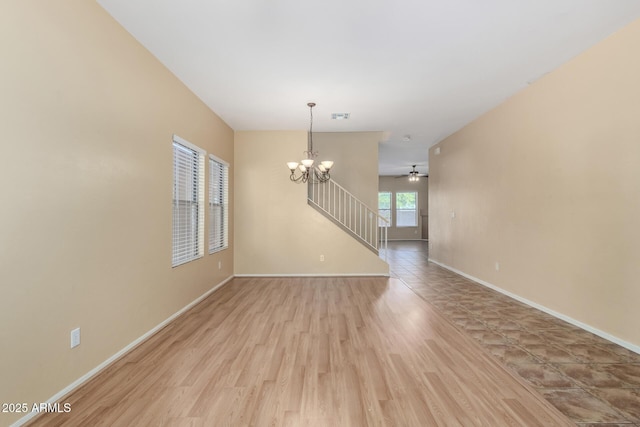 spare room featuring ceiling fan with notable chandelier and light hardwood / wood-style flooring