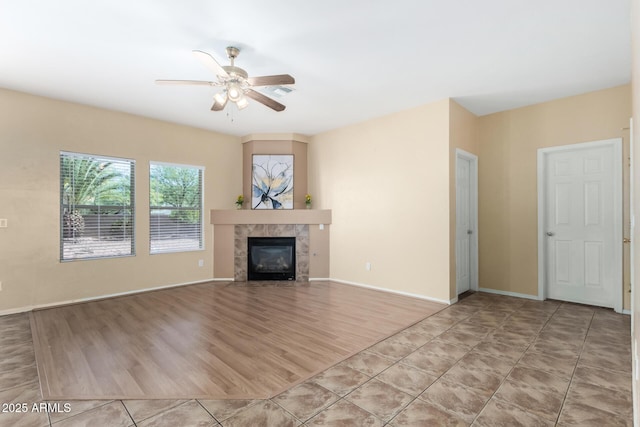 unfurnished living room with ceiling fan, a tile fireplace, and light tile patterned floors