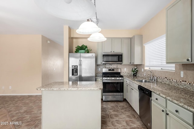 kitchen featuring appliances with stainless steel finishes, decorative light fixtures, sink, backsplash, and a center island